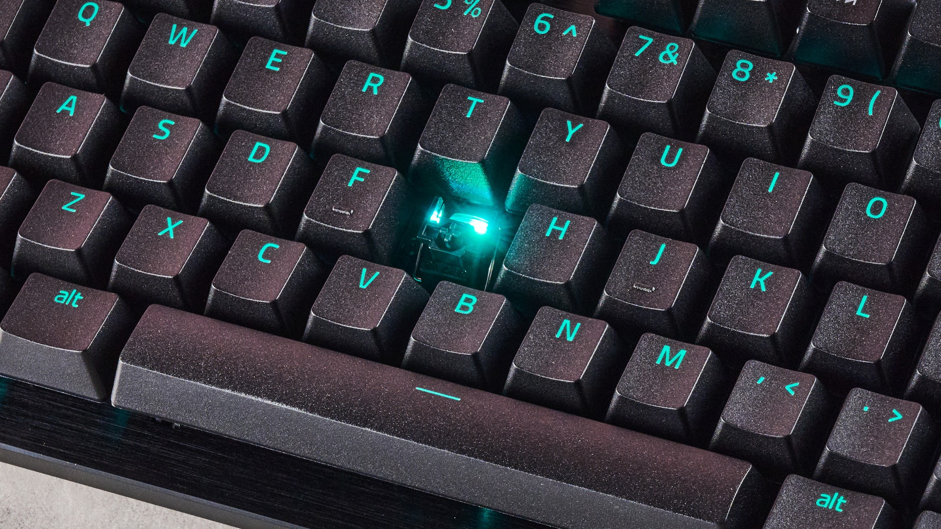 Close-up of switch underneath G key, with keycap removed and green RGB lighting, on the Razer Huntsman V3 Tenkeyless 8KHz