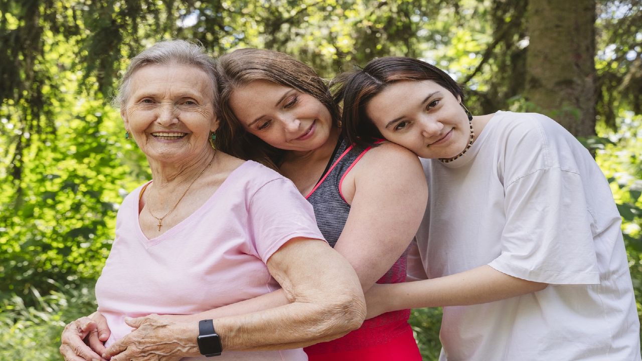 A grandmother, mother and daughter hug each other.