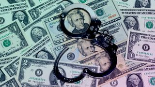 A pair of handcuffs resting on some dollars.