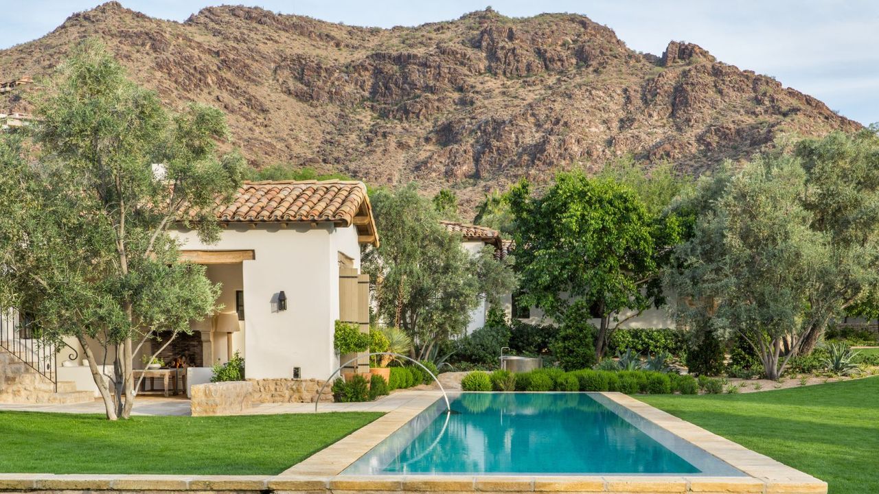 House exterior with pool in foreground and mountain and house in background