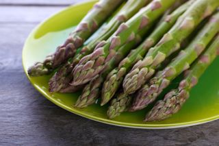 Freshly cut asparagus on a green plate.