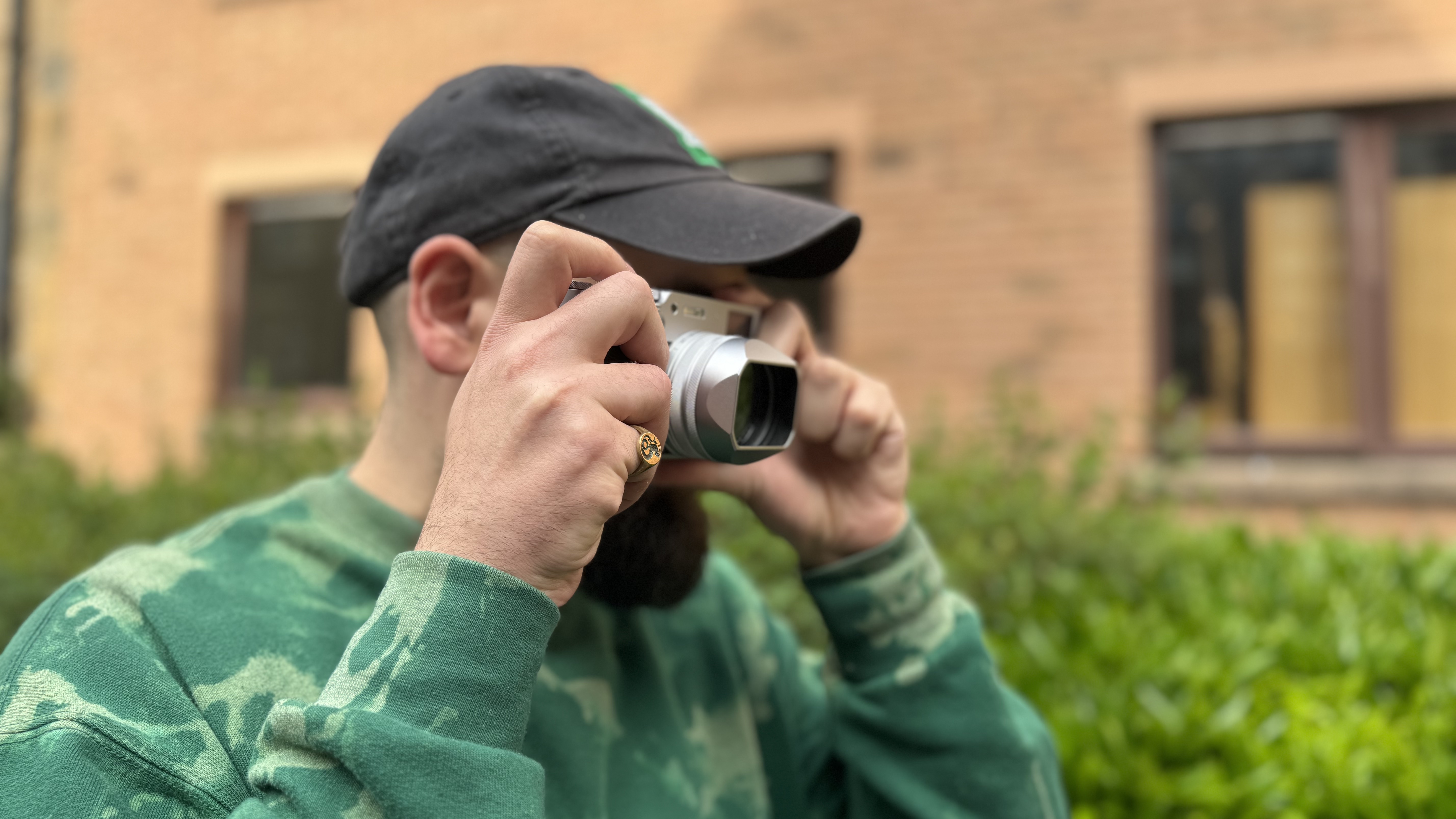 A man in a green jumper taking photos with the Fujifilm X100VI