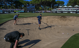 Groundskeepers tidy up beers cans in a bunker at LIV Golf Australia
