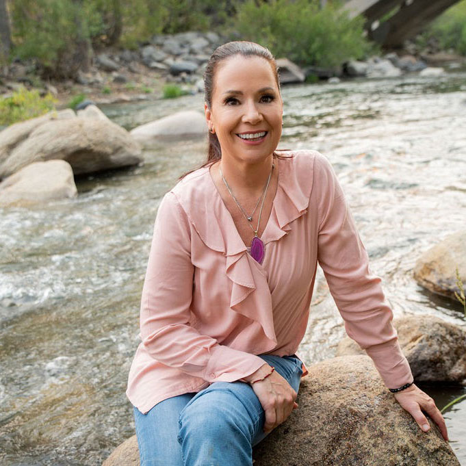Woman on rock with hair tied back and pink cardigan is Feng Shui practitioner Kerstin Tracy
