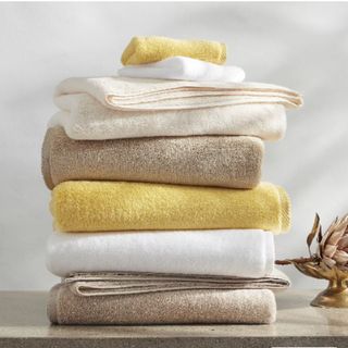A stack of Matouk Milagro Towels against a white wall.