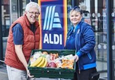An aldi worker and a charity worker holding a basket of donated food