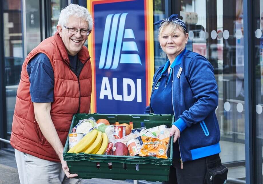 An aldi worker and a charity worker holding a basket of donated food
