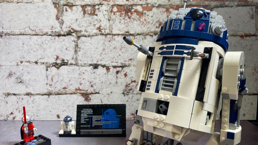 Lego R2-D2 with tools out beside an R2 minifig on display plaque and Darth Malak, all against a brick wall