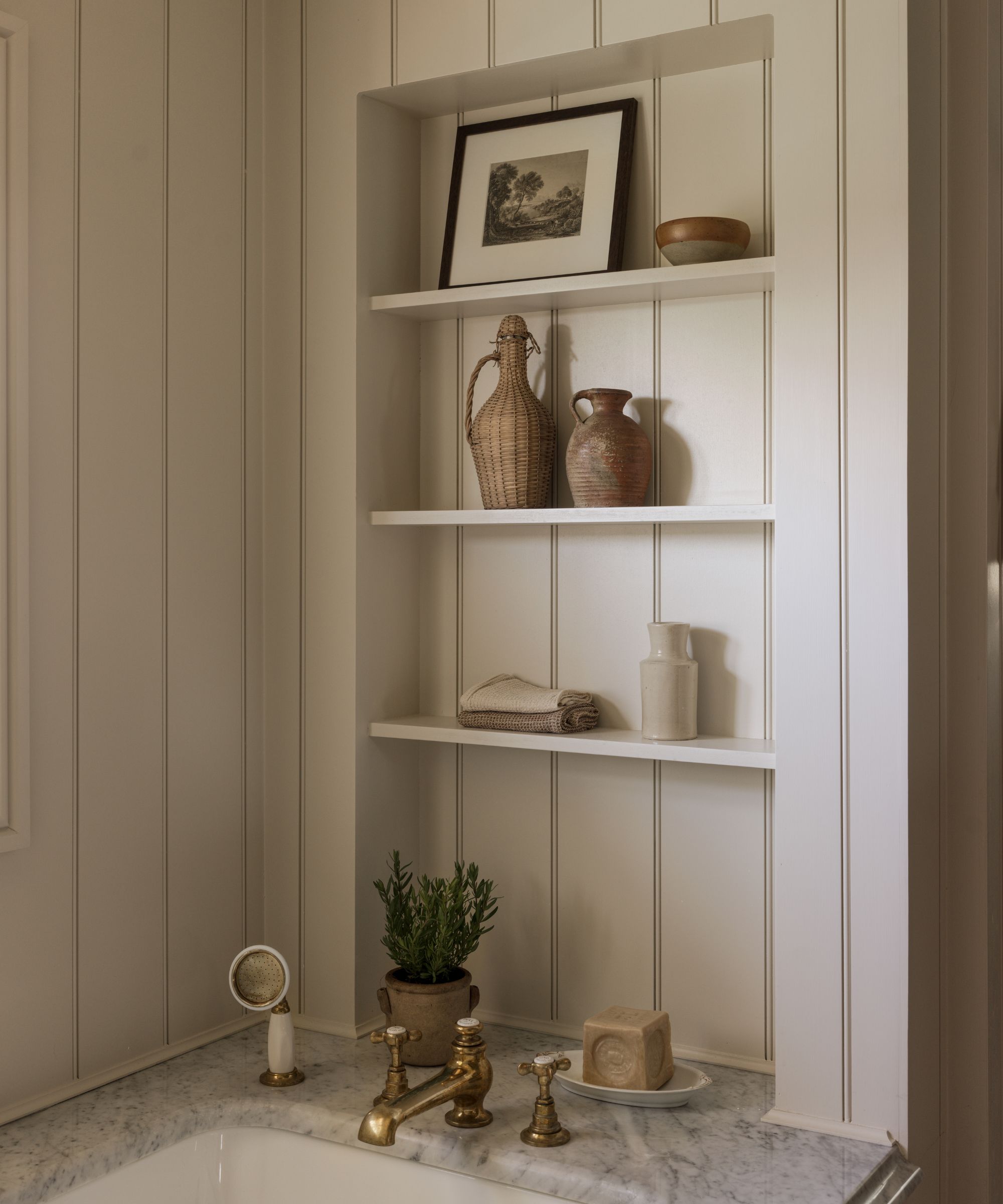 A cozy bath nook with paneled walls and recessed shelving