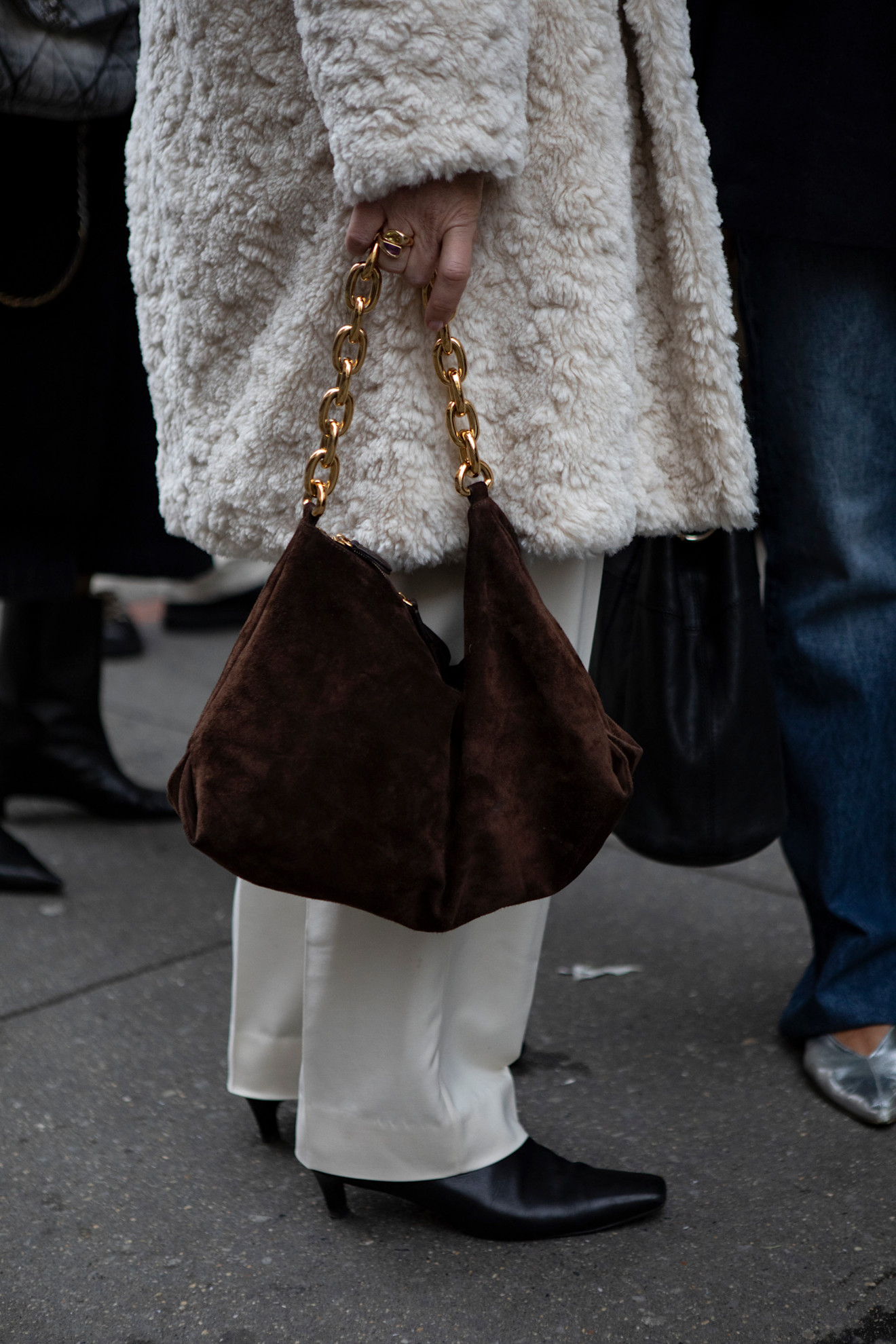 woman weaing all-white with a slouchy suede bag.
