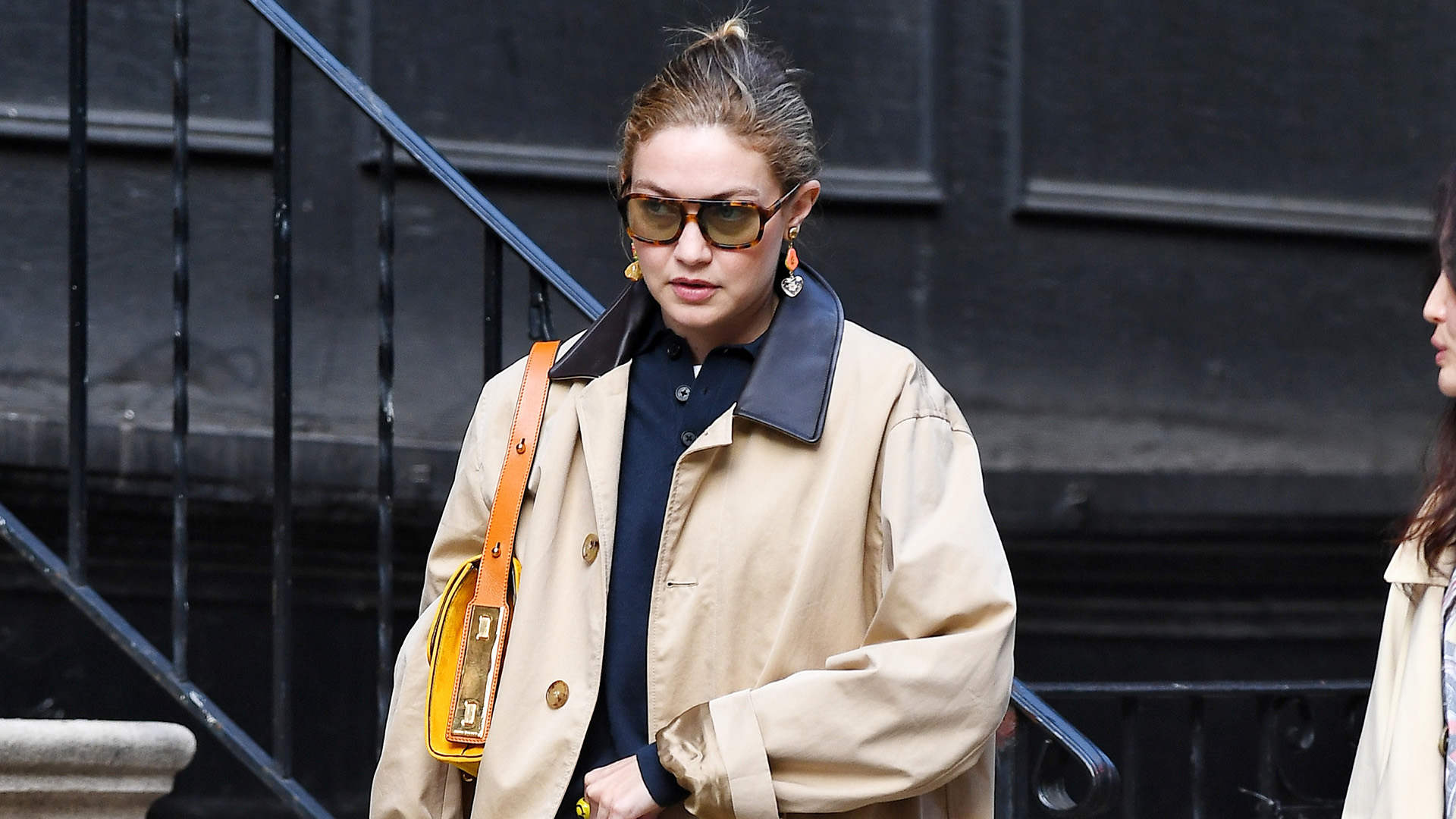 Gigi Hadid wearing a trench, polo top, light-wash jeans, and red Miu Miu loafers
