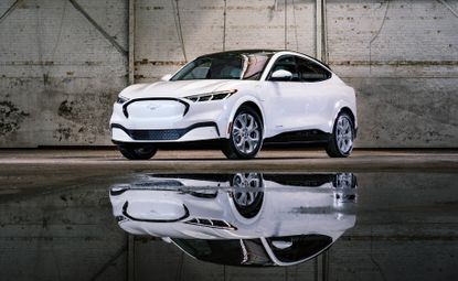 White car parked beside water, with reflection showing