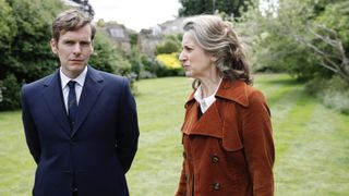 Shaun Evans in a dark suit as Endeavour walks alongside Abigail Thaw in a brown coat as Dorothea Frazil in Endeavour.