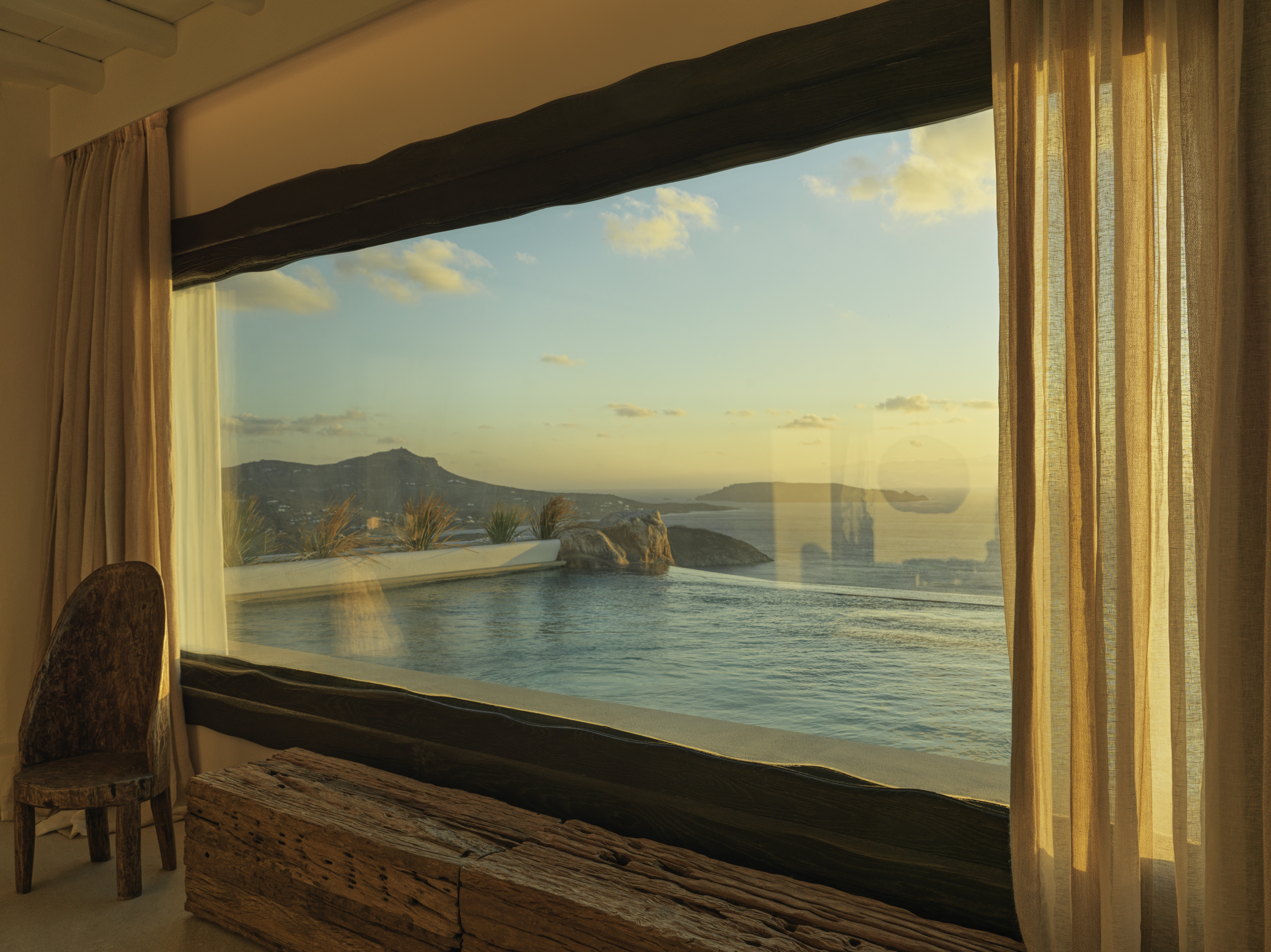 A golden sunset, as seen from inside a pool-view room dressed in crafty wooden furniture.