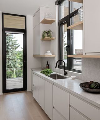 neutral modern kitchen with light gray cabinets and black window and doorframes