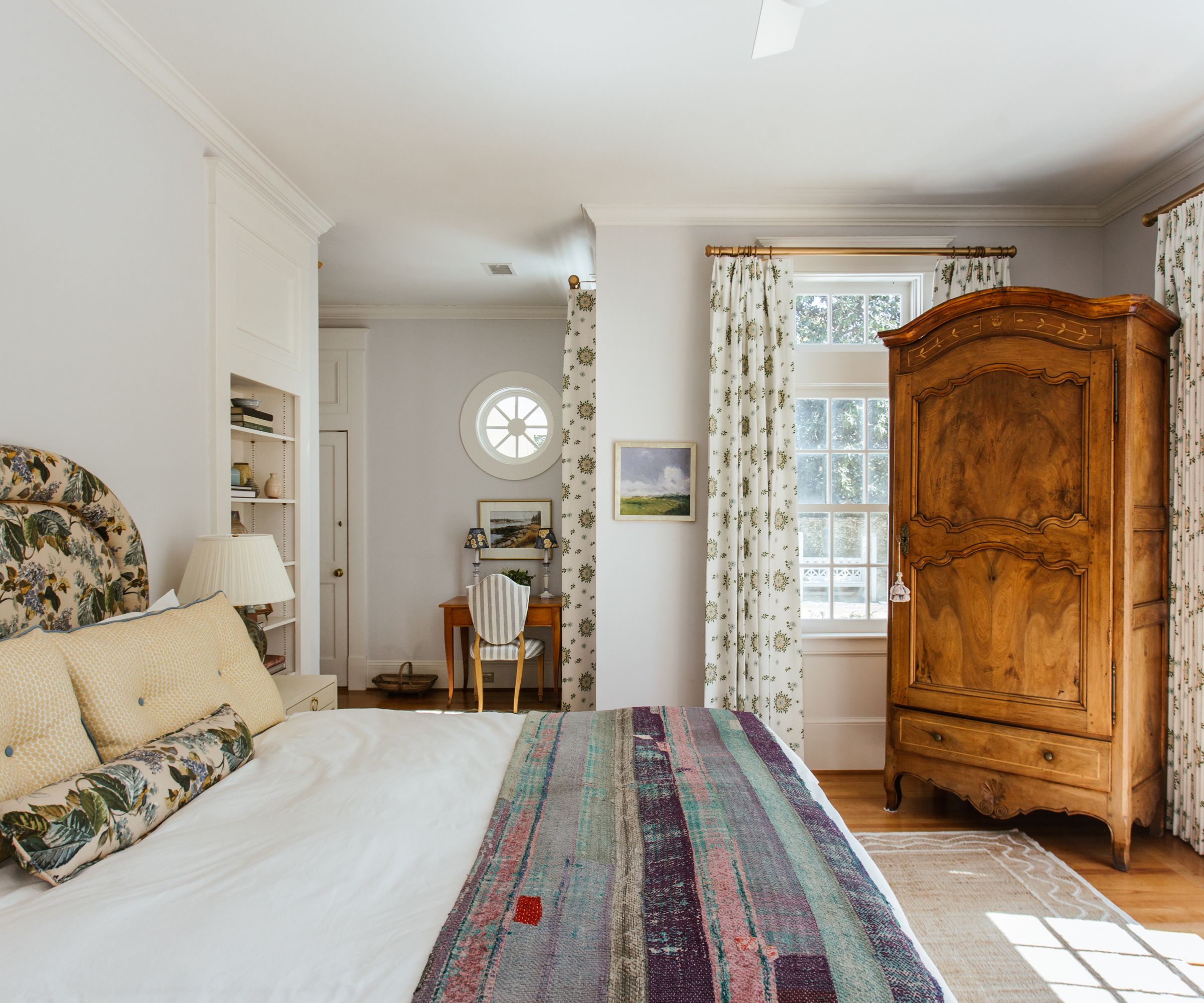 vintage nancy meyers style bedroom with an antique armoire and patterned floral headboard