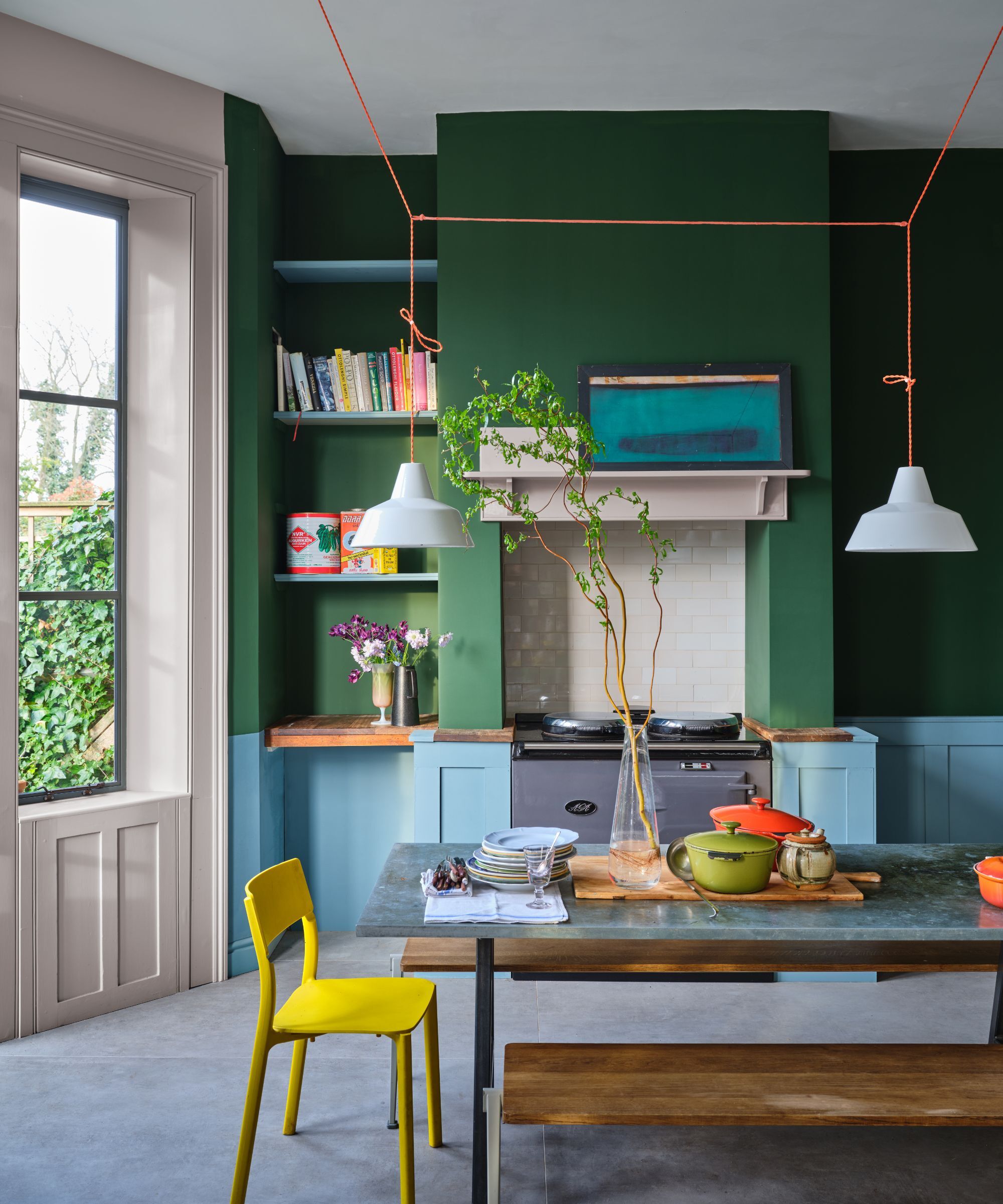 A large kitchen with bottle green walls and blue cabinets