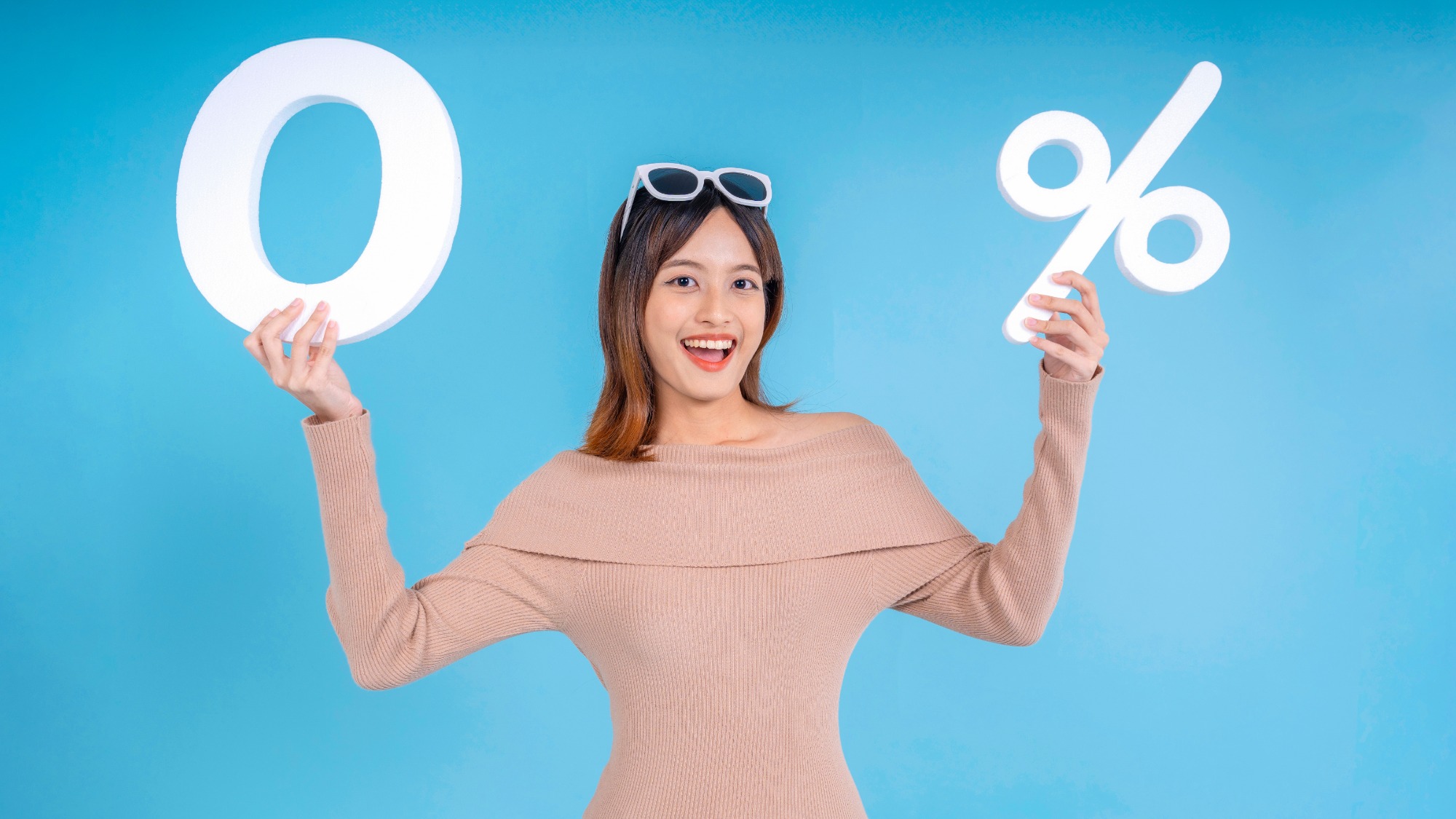 Woman standing and holding white zero and percent symbols on light blue background