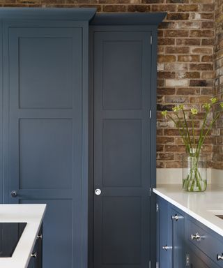 Pantry door ideas with dark blue shaker style doors and exposed brick wall