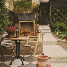 Wooden bistro set on patio area with log shed in background