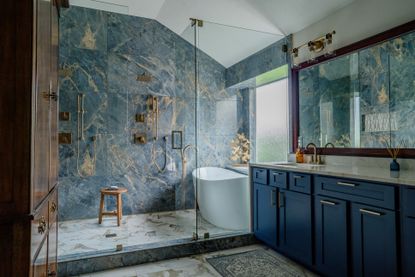 A bathroom with a blue stone on walls, and gold-plated hardwaree