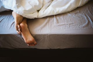 Feet poking out of the bottom of bed sheets