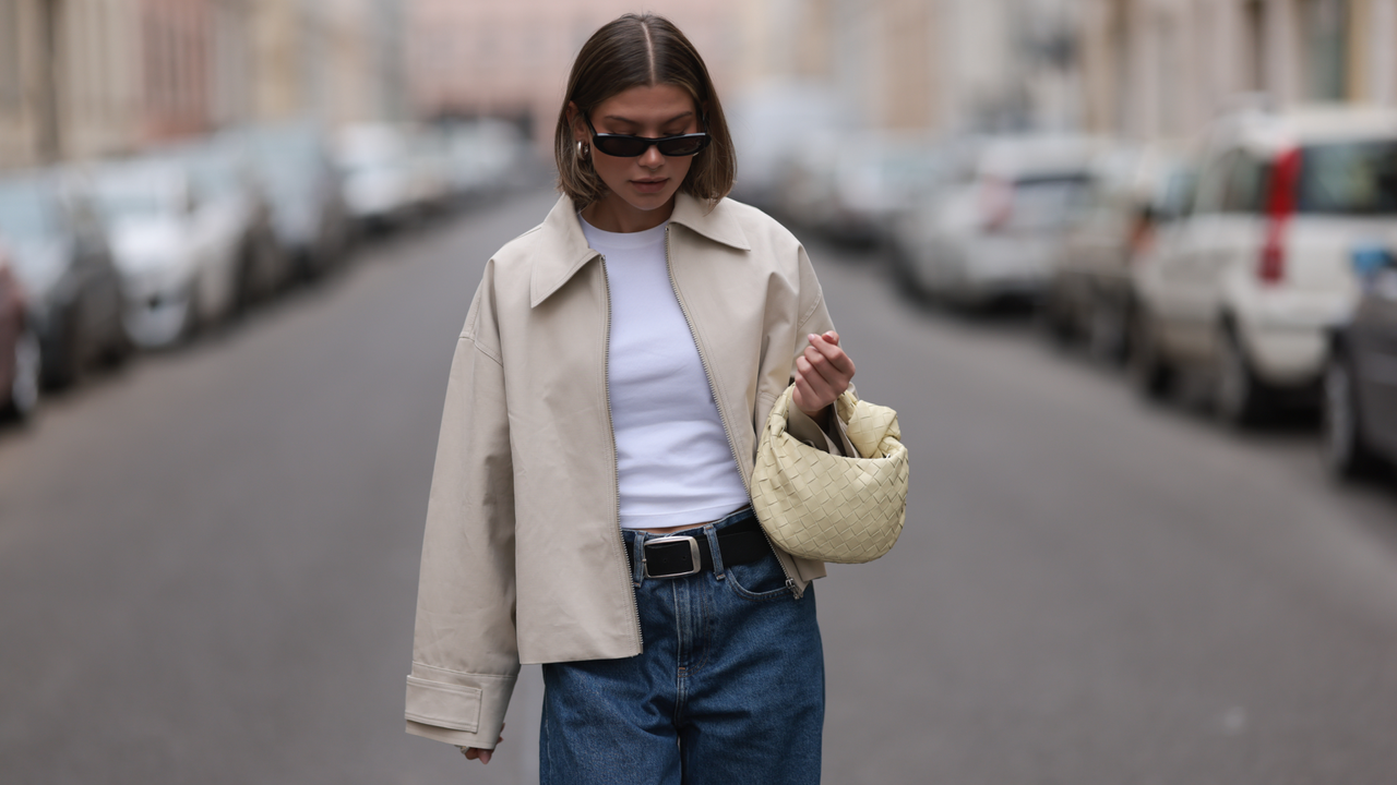  Sophia Geiss seen wearing Saint Lauren black sunglasses, Uniqlo white cotton basic top, Calvin Klein blue denim baggy wide leg jeans pants, black leather belt, Meotine creamy white canvas jacket, Bottega Veneta creamy white / vanilla leather mini Jodie bag, on April 12, 2024 in Berlin, Germany. (Photo by Jeremy Moeller/Getty Images)