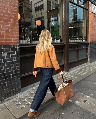 woman wearing cuffed denim outfit with suede jacket and bag