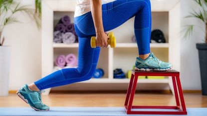 Woman doing dumbbell lunges onto a step