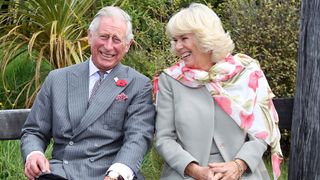King Charles and Queen Camilla sitting on a bench laughing