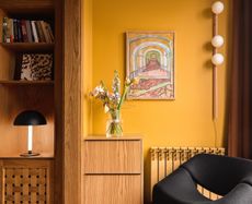A corner in the living room with ochre walls and a black chair
