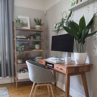 Home office with grey walls, industrial desk, grey chair, open shelving and house plants