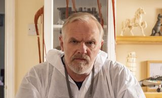 Greg Davies as Wicky sitting in a white suit in front of a crime scene for The Cleaner season 2