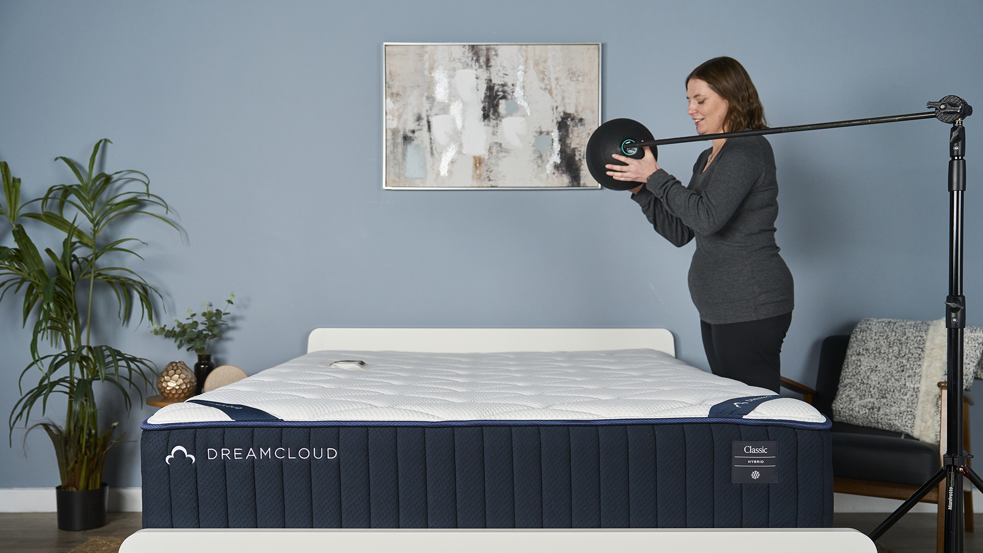 A Tom's Guide tester holds a 5kg slam ball over the DreamCloud Classic and then drops it, while an accelerometer on the other side of the mattress measures how much motion is absorbed