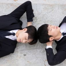 two young men lay on the ground resting their head in their hands in a still from the bl kdrama where your eyes linger