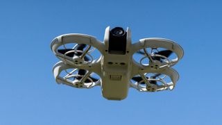 DJI Neo drone flying, blue sky behind, seen from below