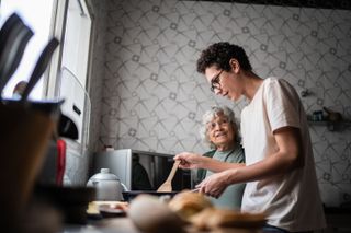 A grandmother and a teenage boy cooking together