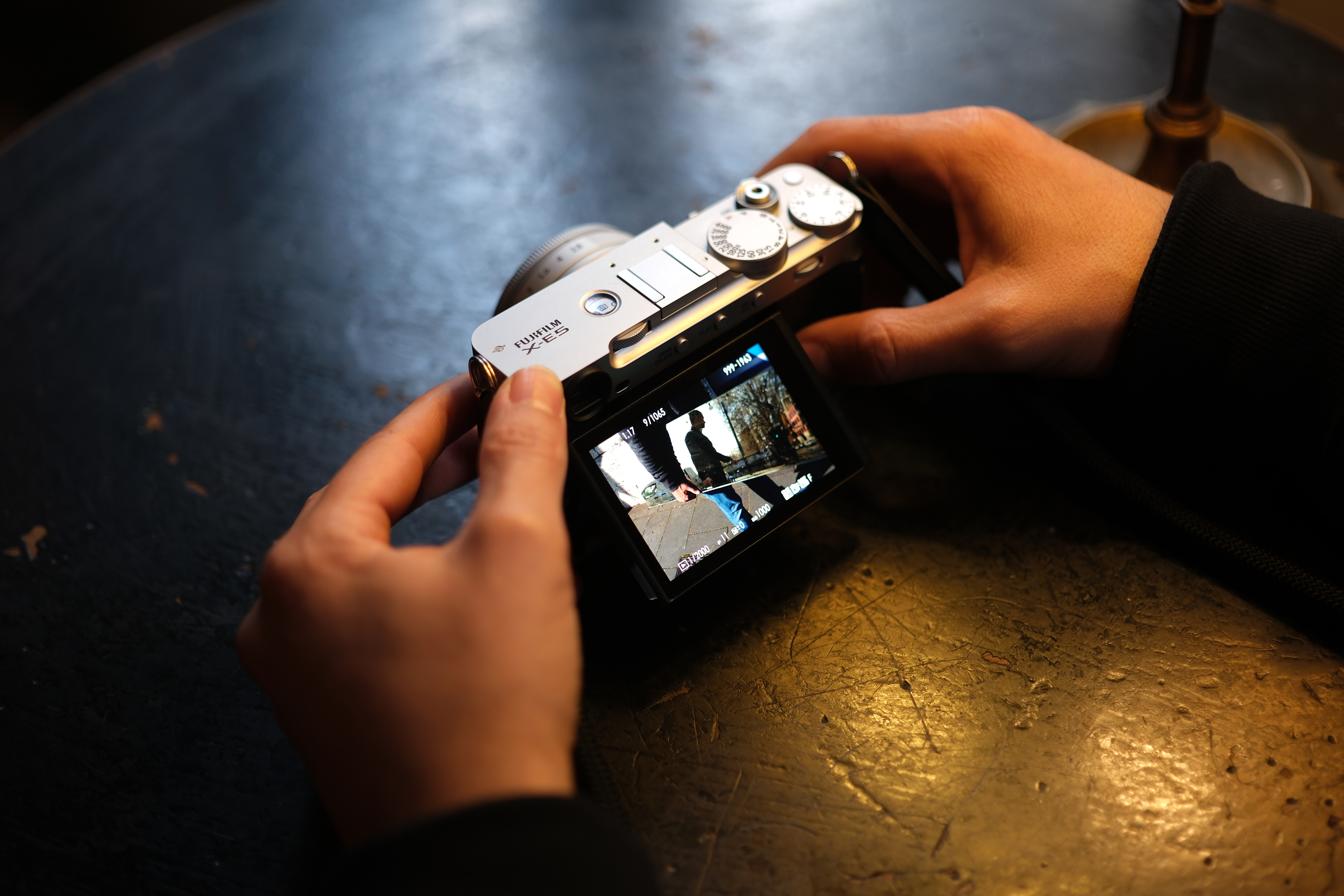 The Fujifilm X-E5 in hand, with the rear screen in use to compose