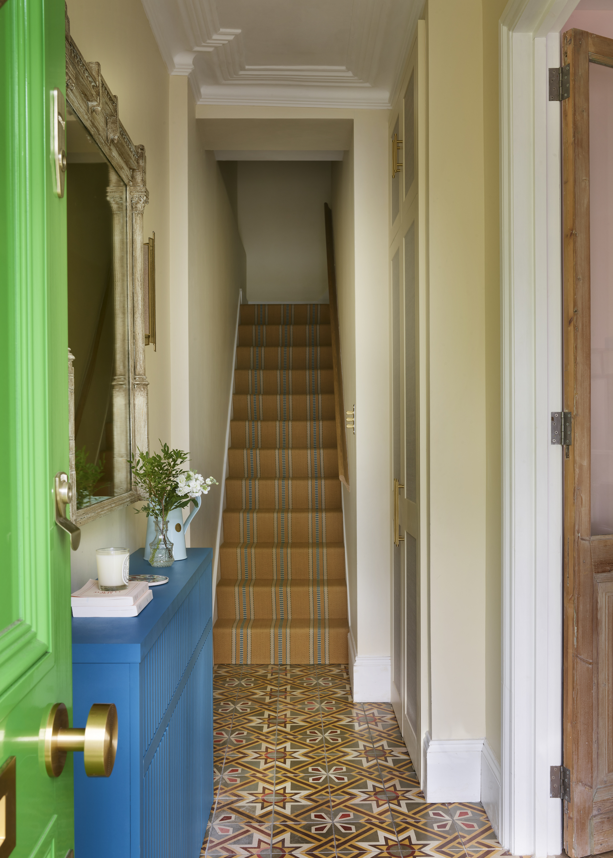 staircase with striped runner and green door