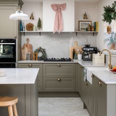 Kitchen with greige cabinets and white worktops, covered in christmas decorations and usual kitchen items