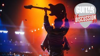 A guitarist, pictured in shadow from behind, holds their guitar aloft in front of a crowd