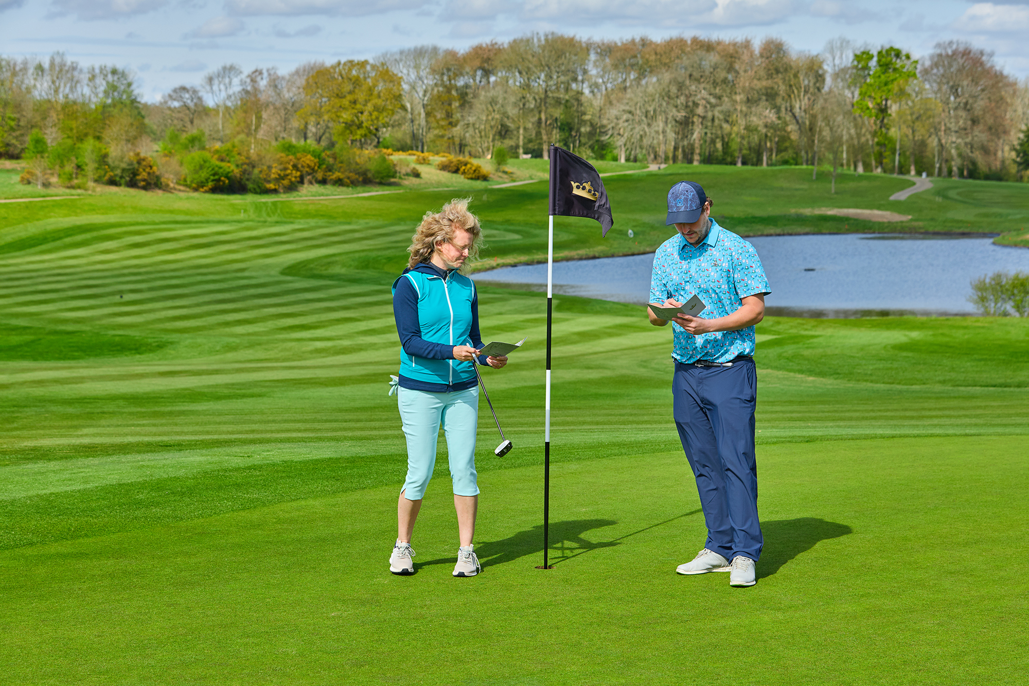 Two golfers marking their score after completing a hole on the course