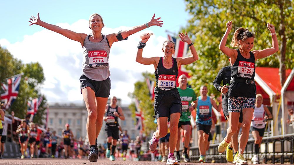 Runners celebrate as they run down The Mall towards the finish of The 2021 Virgin Money London Marathon