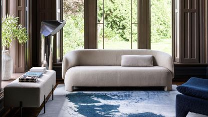 living room with large windows, a white boucle sofa and an ink blue marbling effect rug