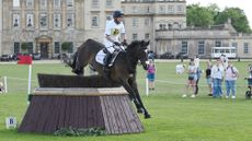 Harry Meade and Cavalier Crystal jump a cross-country fence in front of Badminton House in 2025.
