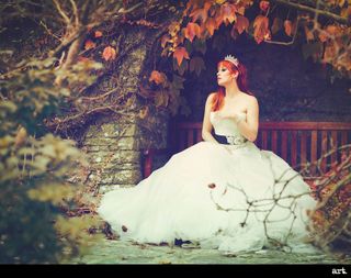 An image of a redheaded woman in a wedding dress, sitting outdoors surrounded by autumn leaves, taken with the Olympus Vintage I Art FIlter