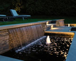 contemporary backyard pond with waterfall effects and outdoor lighting