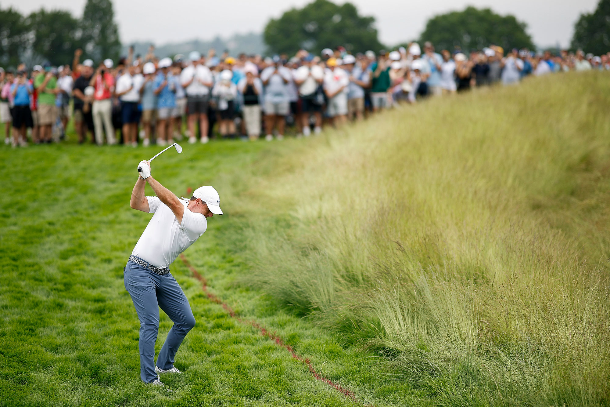 Rory McIlroy hitting a shot from thick rough at Oakmont Country Club after missing the fairway at the US Open