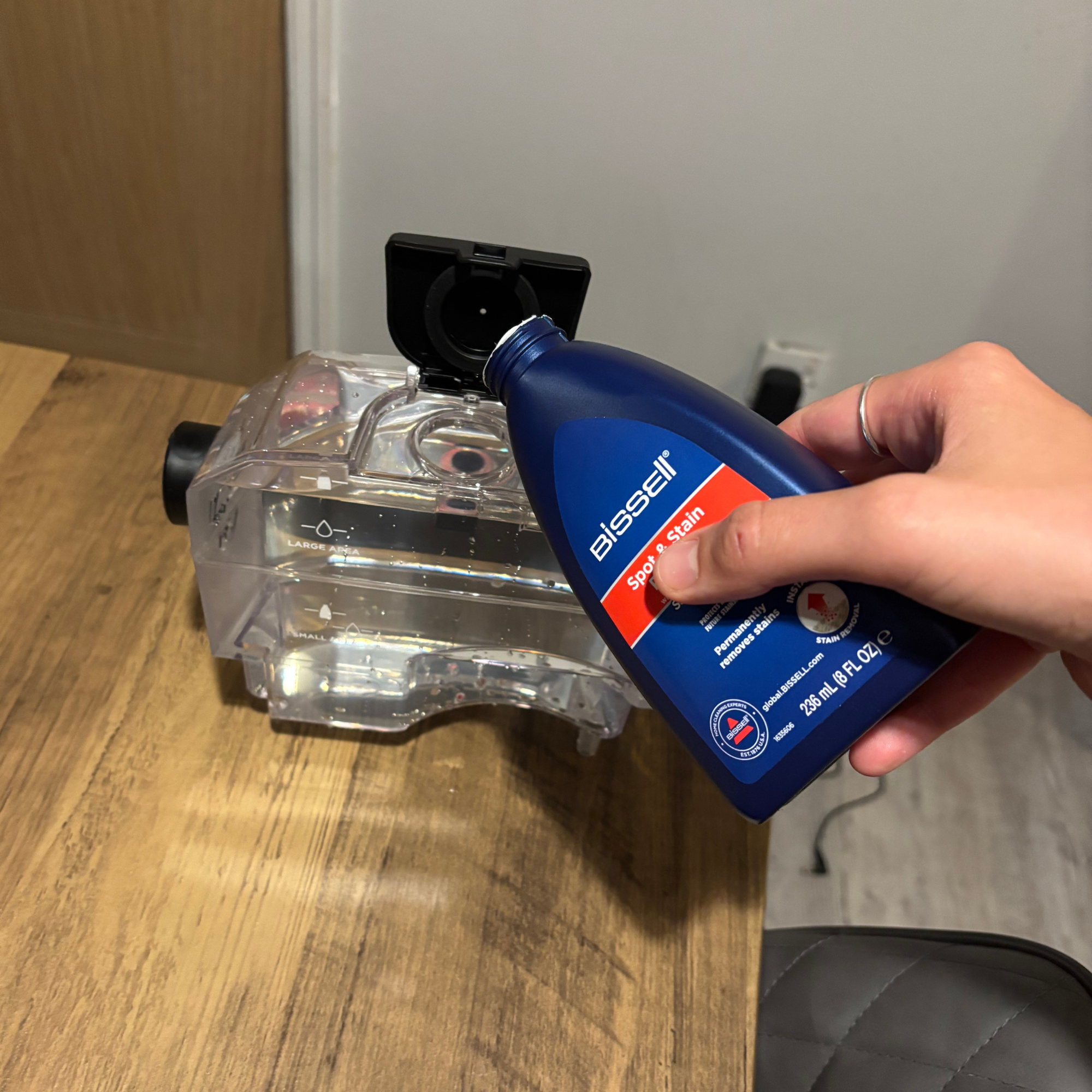 Bottle of cleaning solution being poured into the spot clean water tank