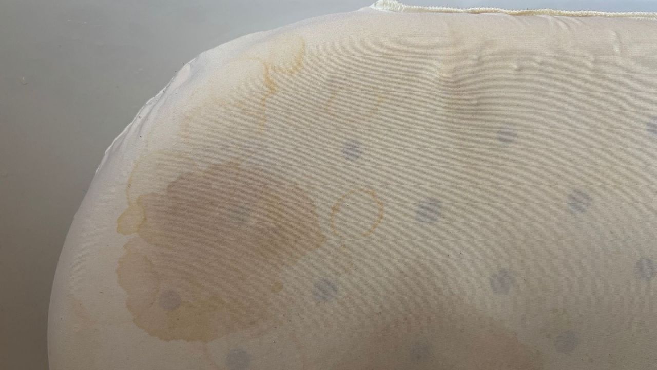 The image shows yellow and brown stains on a memory foam pillow